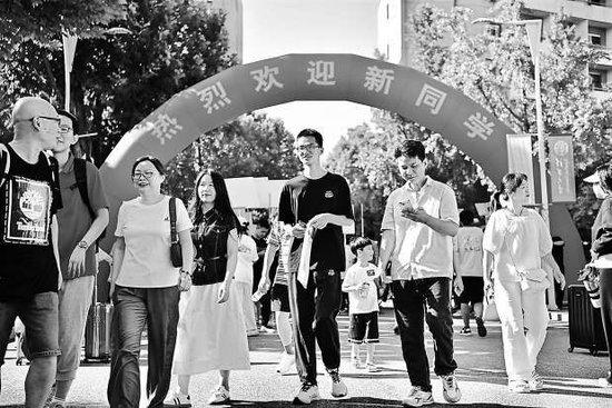 今天上午，清华大学新生及家长走过“热烈欢迎新同学”的红色拱门步入校园。 本报记者 和冠欣 摄